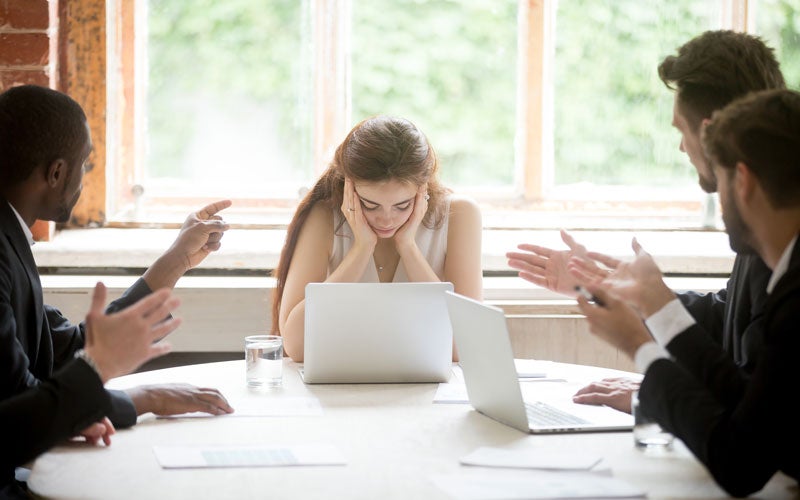 Stressed woman surrounded by arguing colleagues